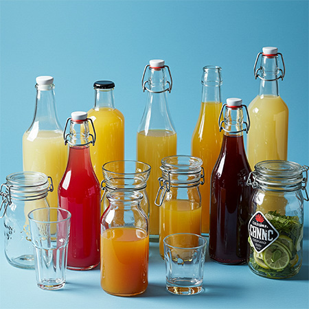 gastronomie Image d'ambiance : verres et bouteilles remplis de jus et de fruits sur un fond bleu clair