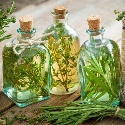 Trois bouteilles en verre transparent remplies d'huile aromatisée, fermées par un bouchon en liège