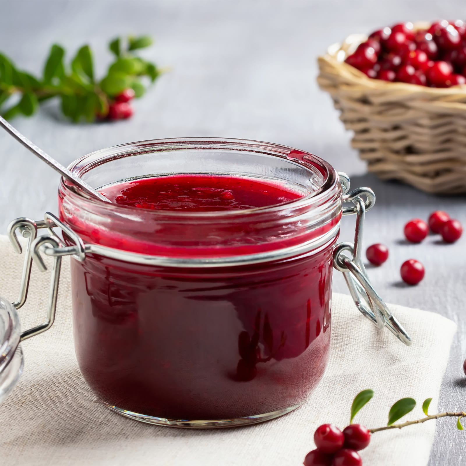 Petit pot en fil de fer rempli de confiture rouge maison, disposé sur une serviette en tissu avec des baies rouges